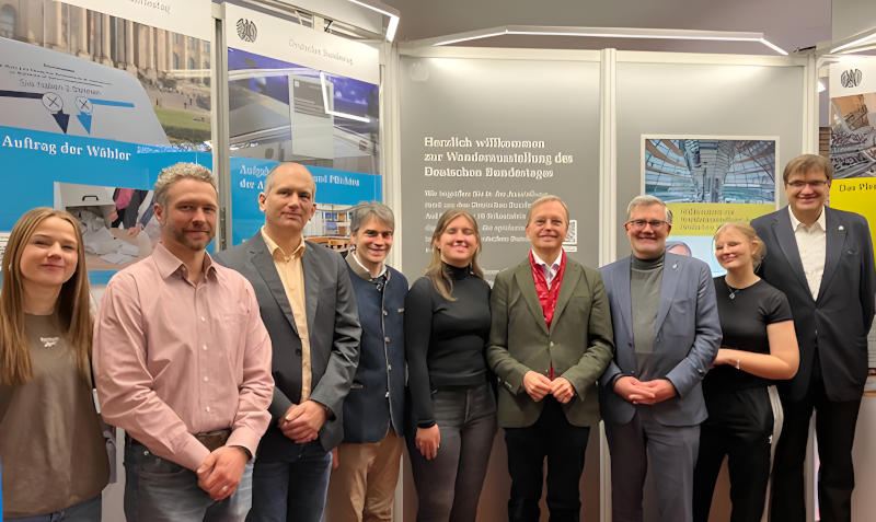 Schüler*innen, Lehrer*innen und Politiker*innen vor einer Tafel der Wanderausstellung des deutschen Bundestags.