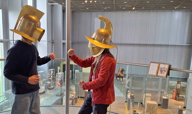 Wwei Schüler*innen in römischen Helmen im Museum des LVR Rheinland, Xanten.