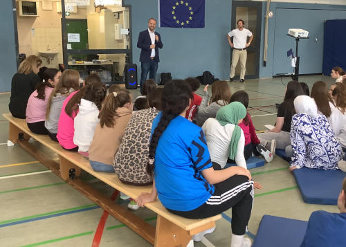 Eine Gruppe von Schüler*innen und ein Europapolitiker in einer Turnhalle