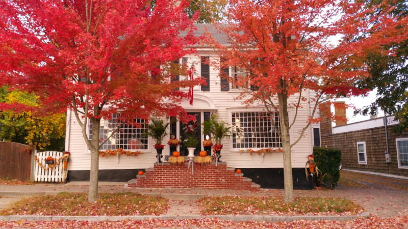 Bäume mit rotem Laub vor einem weißen Holzhaus in Rhode Island, USA